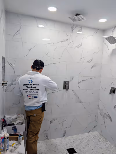 Diamond State Plumbing technician completing a custom shower installation with rain head