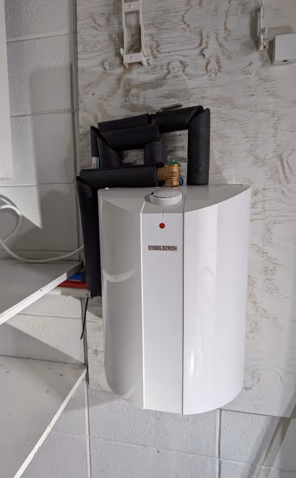 Stiebel Eltron point-of-use tankless water heater with insulated pipe connections mounted on a wall